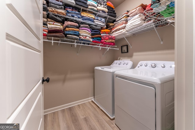 laundry area featuring separate washer and dryer and light hardwood / wood-style floors