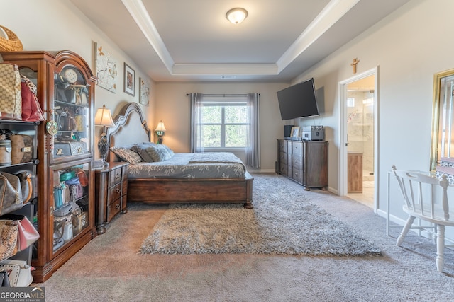 bedroom with ensuite bath, a tray ceiling, and light carpet