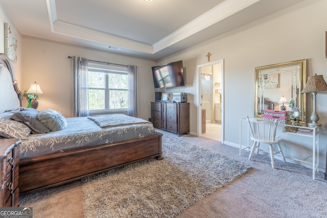 carpeted bedroom with connected bathroom, a tray ceiling, and ornamental molding