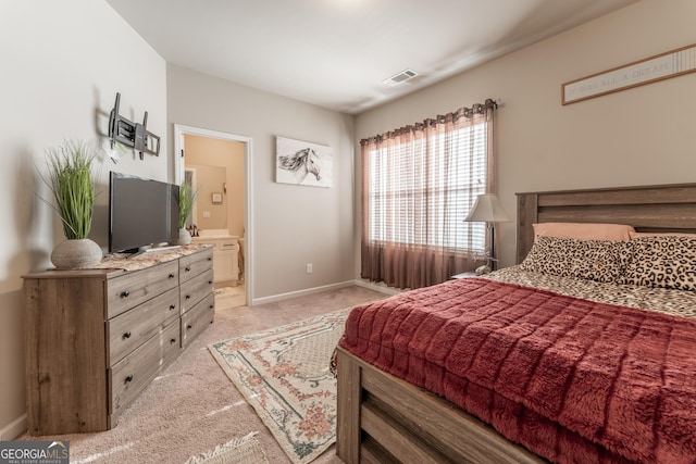 bedroom with connected bathroom and light colored carpet