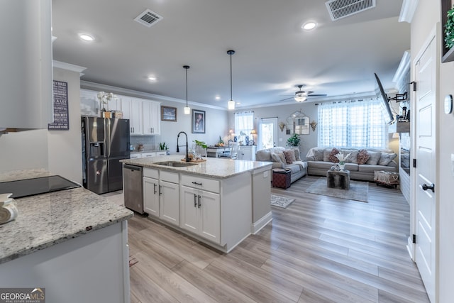 kitchen with sink, white cabinetry, light stone counters, decorative light fixtures, and stainless steel appliances