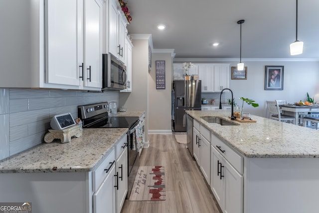 kitchen with pendant lighting, an island with sink, sink, white cabinets, and stainless steel appliances