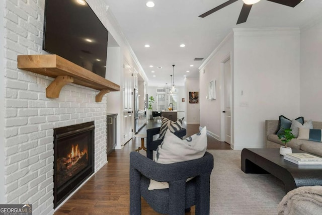 living room featuring ornamental molding, a brick fireplace, dark hardwood / wood-style floors, and ceiling fan