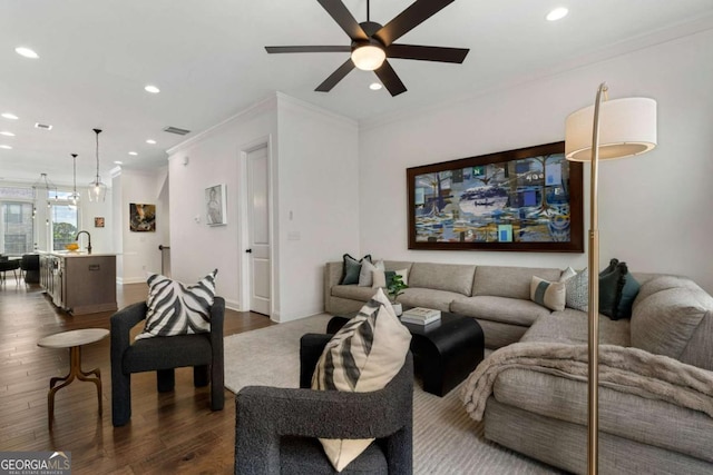 living room featuring sink, crown molding, dark wood-type flooring, and ceiling fan