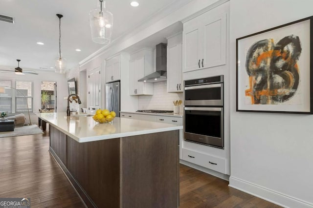 kitchen featuring sink, white cabinetry, stainless steel appliances, a center island with sink, and wall chimney exhaust hood