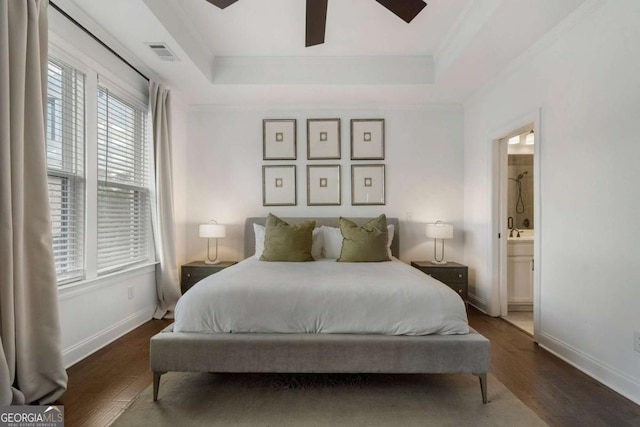 bedroom featuring ensuite bath, a tray ceiling, and dark hardwood / wood-style floors