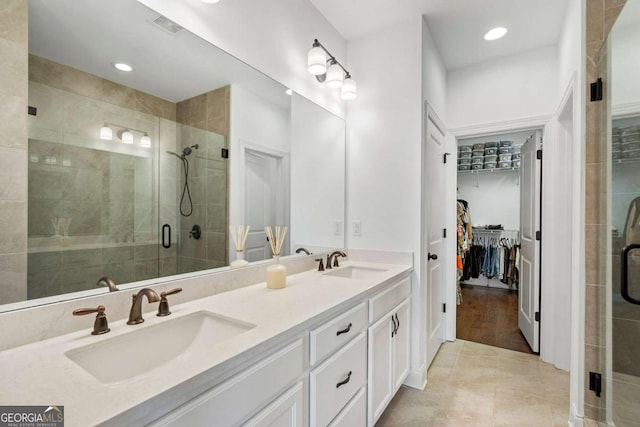 bathroom featuring a shower with door, vanity, and tile patterned floors