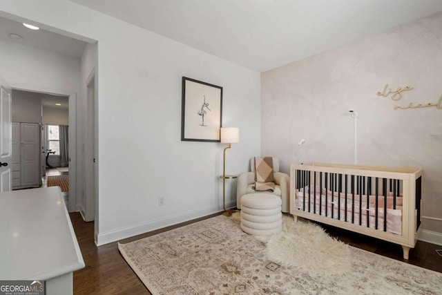 bedroom with a crib and dark hardwood / wood-style floors