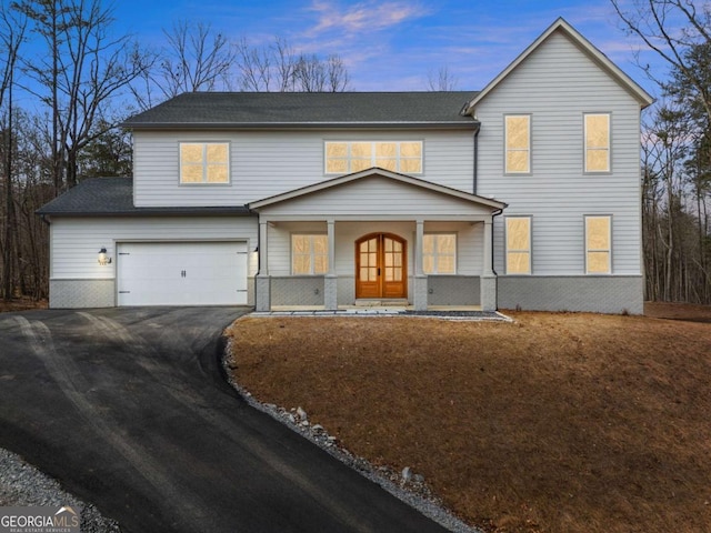 traditional home featuring driveway, french doors, an attached garage, and brick siding