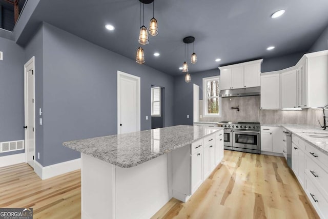 kitchen featuring visible vents, white cabinets, a kitchen island, appliances with stainless steel finishes, and pendant lighting