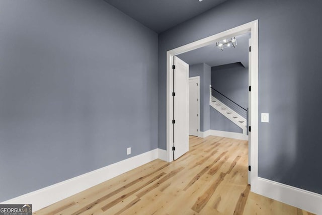 unfurnished room with stairway, baseboards, and wood finished floors