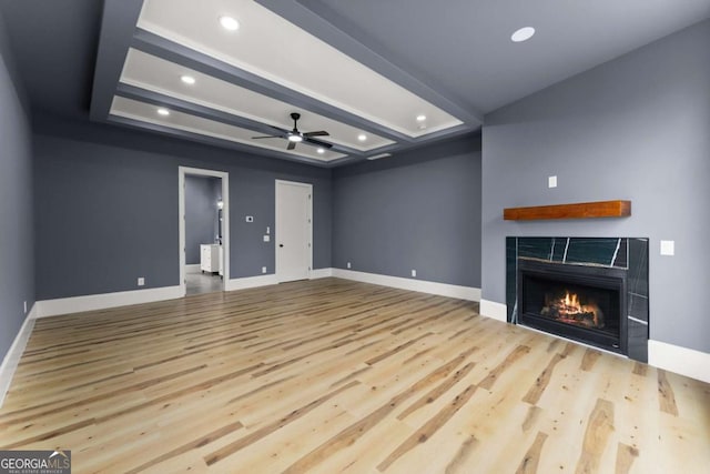 unfurnished living room with light wood finished floors, recessed lighting, a tiled fireplace, a ceiling fan, and baseboards