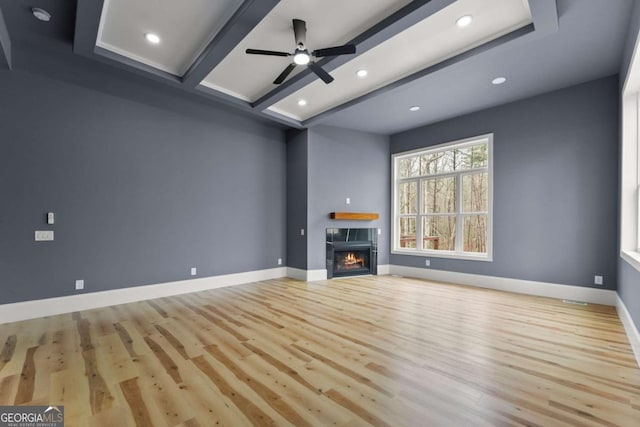 unfurnished living room featuring ceiling fan, baseboards, beam ceiling, light wood finished floors, and a tiled fireplace