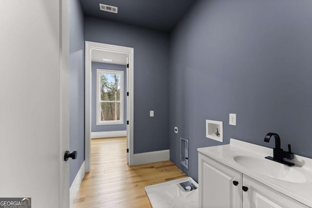 bathroom featuring visible vents, vanity, baseboards, and wood finished floors