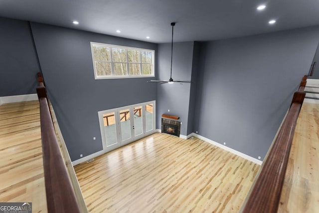 unfurnished living room with baseboards, a glass covered fireplace, and light wood-style floors