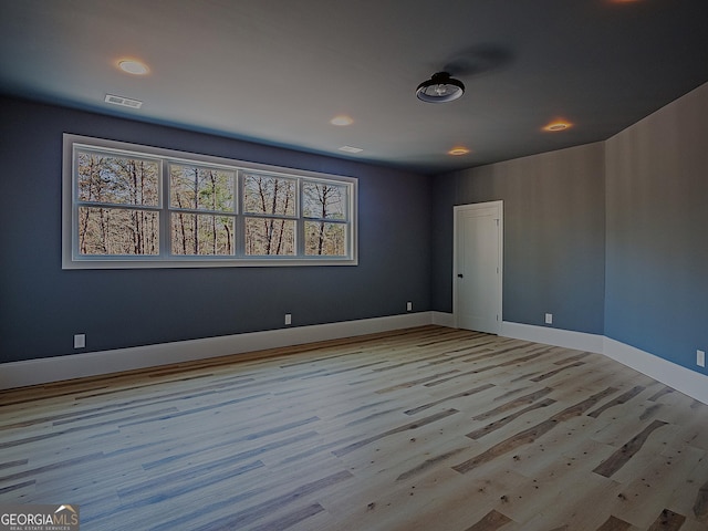 unfurnished room featuring light wood-type flooring, visible vents, and baseboards