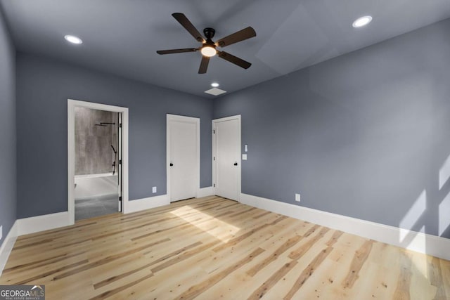 unfurnished bedroom featuring ensuite bath, light wood-style flooring, and baseboards