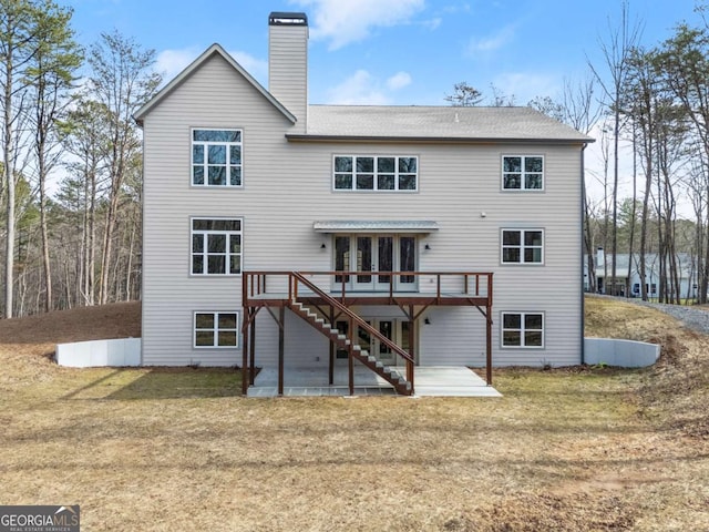 rear view of house featuring a chimney, stairs, a deck, a yard, and a patio area