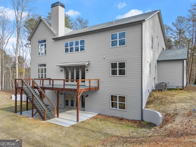 rear view of property with a patio, a chimney, a lawn, a wooden deck, and stairs