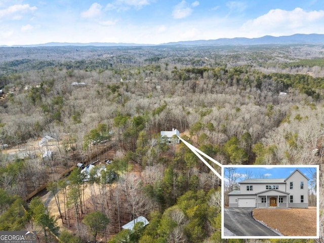 aerial view featuring a wooded view and a mountain view