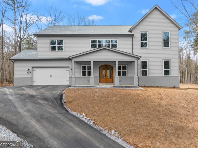 view of front of property with an attached garage, aphalt driveway, french doors, and brick siding