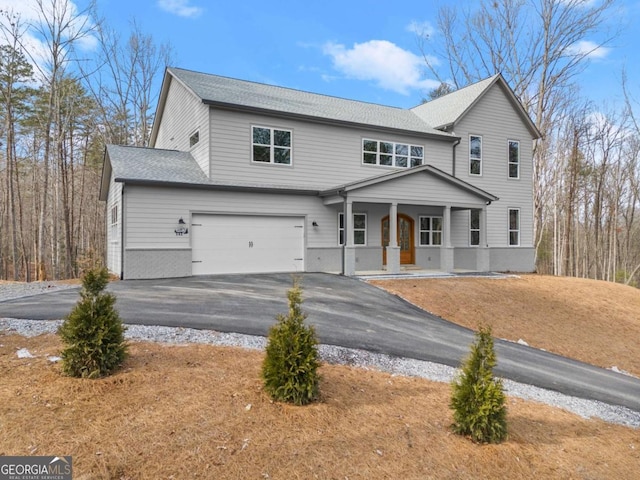 view of front of property featuring covered porch, driveway, a shingled roof, and an attached garage