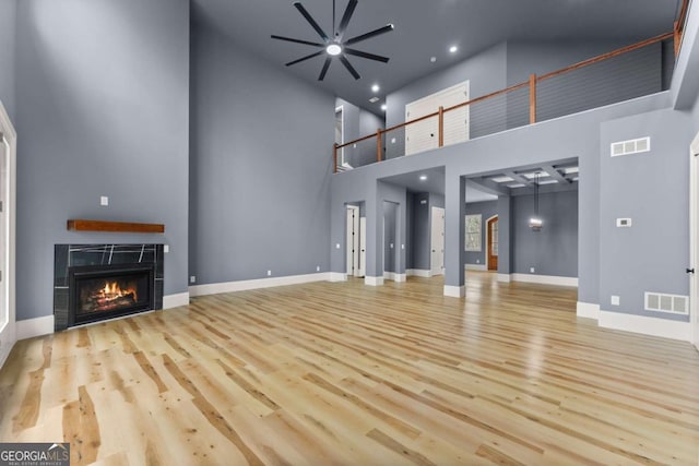 unfurnished living room featuring a warm lit fireplace, light wood-style flooring, and visible vents