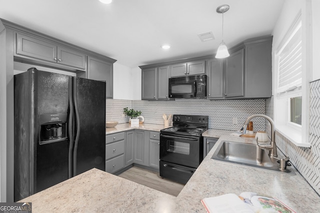 kitchen featuring sink, gray cabinetry, backsplash, black appliances, and decorative light fixtures