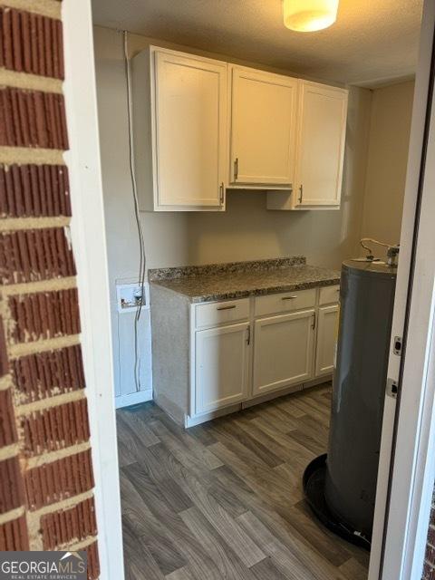 kitchen featuring white cabinetry, dark wood-type flooring, water heater, and dark stone countertops