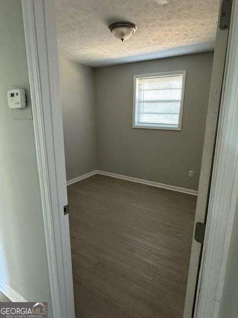 empty room featuring dark hardwood / wood-style floors and a textured ceiling