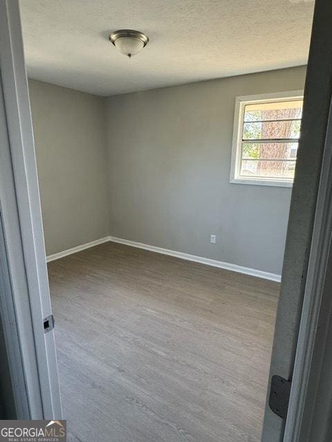 unfurnished room with hardwood / wood-style flooring and a textured ceiling