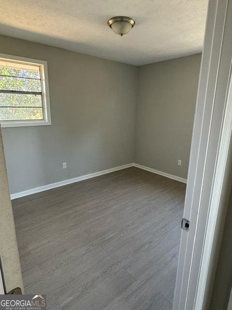 empty room featuring dark wood-type flooring and a textured ceiling