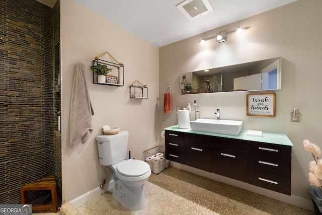 bathroom with vanity, a tile shower, and toilet