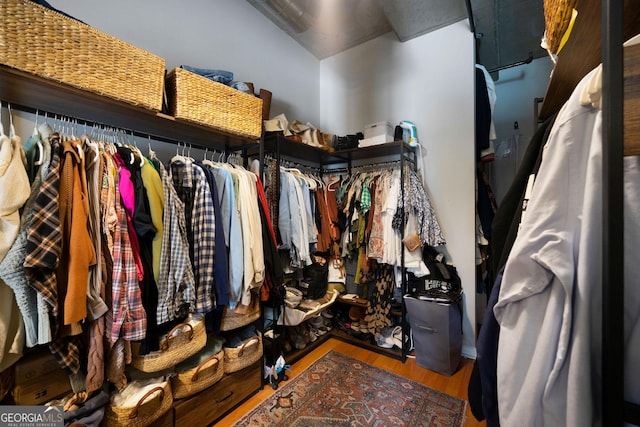 walk in closet with hardwood / wood-style flooring and lofted ceiling