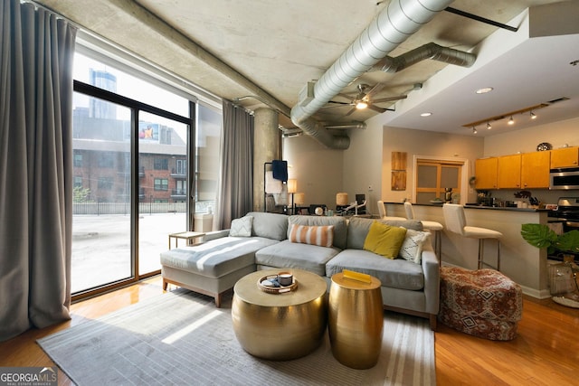 living room featuring ceiling fan, floor to ceiling windows, and light wood-type flooring