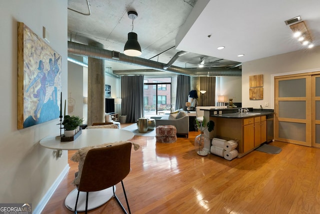 kitchen featuring hanging light fixtures, sink, stainless steel dishwasher, and light hardwood / wood-style floors