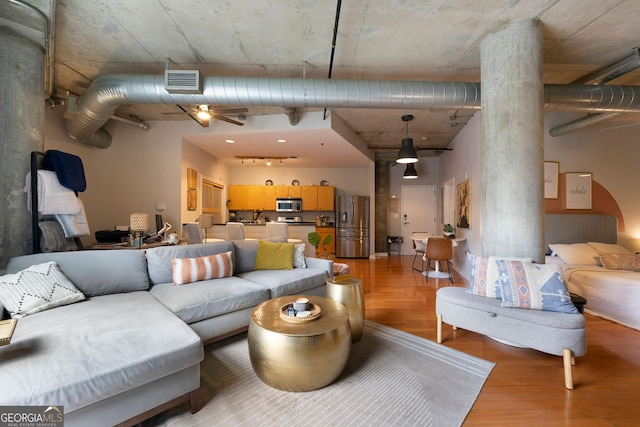 living room with a towering ceiling, light hardwood / wood-style floors, and decorative columns