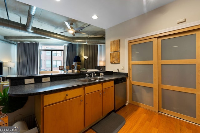 kitchen with sink, stainless steel dishwasher, light hardwood / wood-style floors, and kitchen peninsula