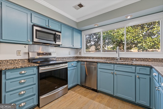 kitchen featuring blue cabinets, sink, crown molding, appliances with stainless steel finishes, and light hardwood / wood-style floors