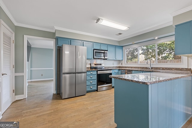 kitchen with light hardwood / wood-style floors, stainless steel appliances, kitchen peninsula, and blue cabinetry