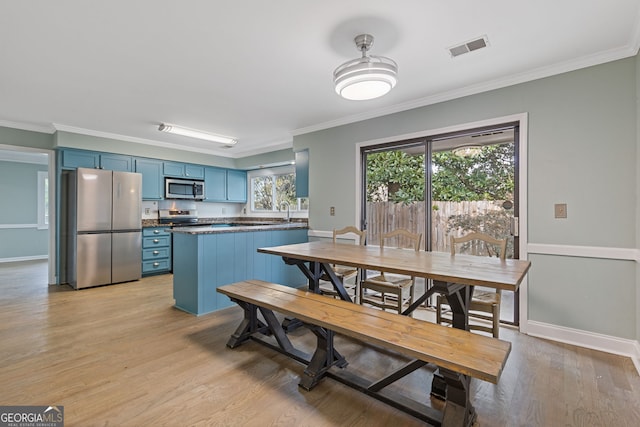 kitchen with ornamental molding, light wood-type flooring, blue cabinetry, and appliances with stainless steel finishes