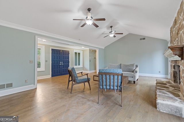 living room with crown molding, lofted ceiling, a fireplace, and light hardwood / wood-style floors