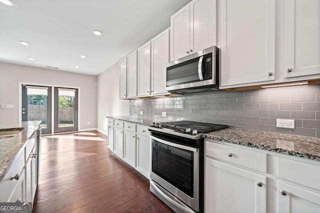 kitchen featuring decorative backsplash, dark wood finished floors, light stone counters, appliances with stainless steel finishes, and white cabinetry