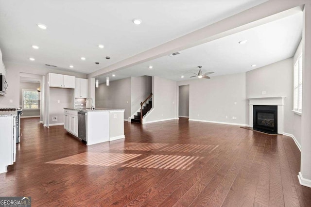 unfurnished living room featuring baseboards, a ceiling fan, a glass covered fireplace, dark wood-type flooring, and recessed lighting