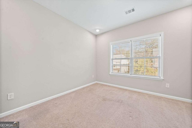 carpeted spare room featuring visible vents and baseboards