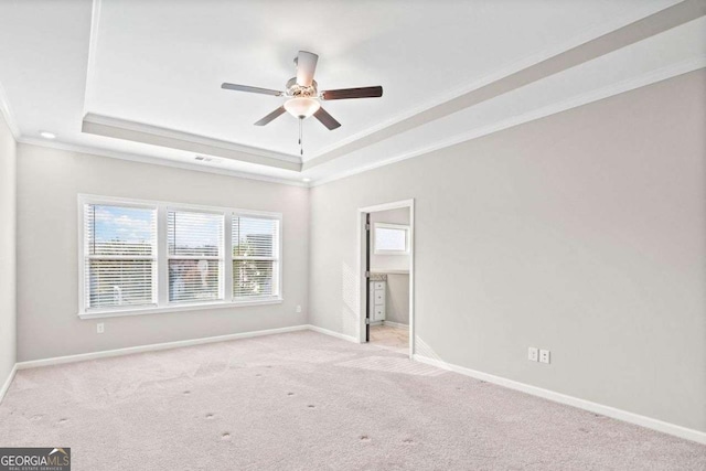 carpeted spare room featuring ceiling fan, ornamental molding, a raised ceiling, and baseboards