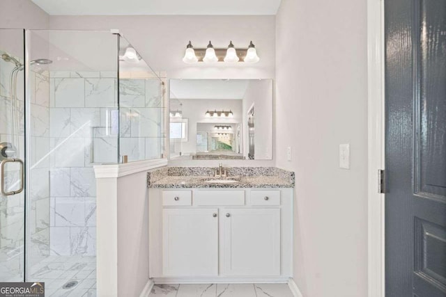 bathroom with marble finish floor, a marble finish shower, vanity, and baseboards