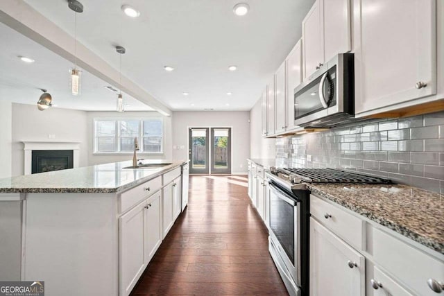 kitchen with dark wood finished floors, tasteful backsplash, appliances with stainless steel finishes, white cabinetry, and a sink