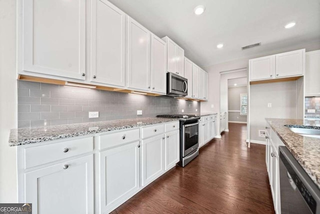 kitchen with appliances with stainless steel finishes, white cabinets, and visible vents