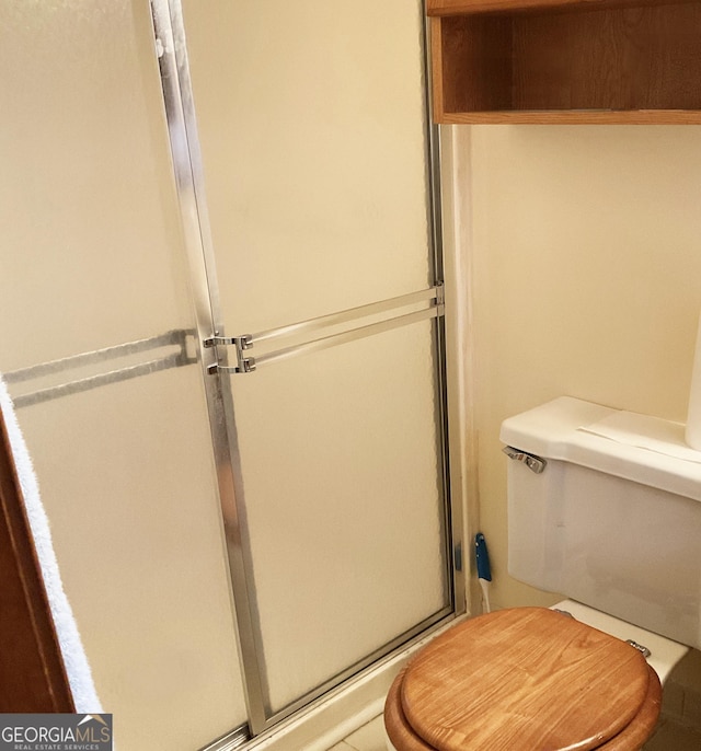 bathroom with a shower with shower door and toilet